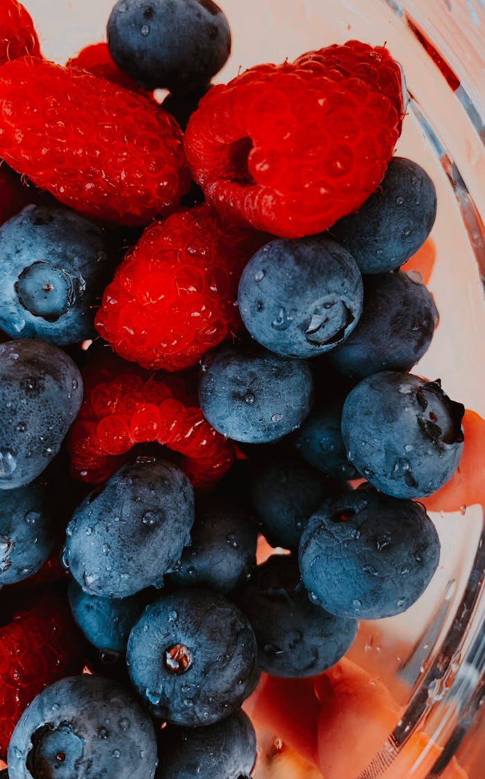 Close-up of fresh blueberries and raspberries with water droplets, showcasing their vibrant colors and freshness.